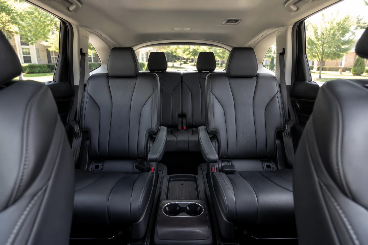The Acura MDX's three-row cabin shown from the second row, lit by natural daylight through the side windows.