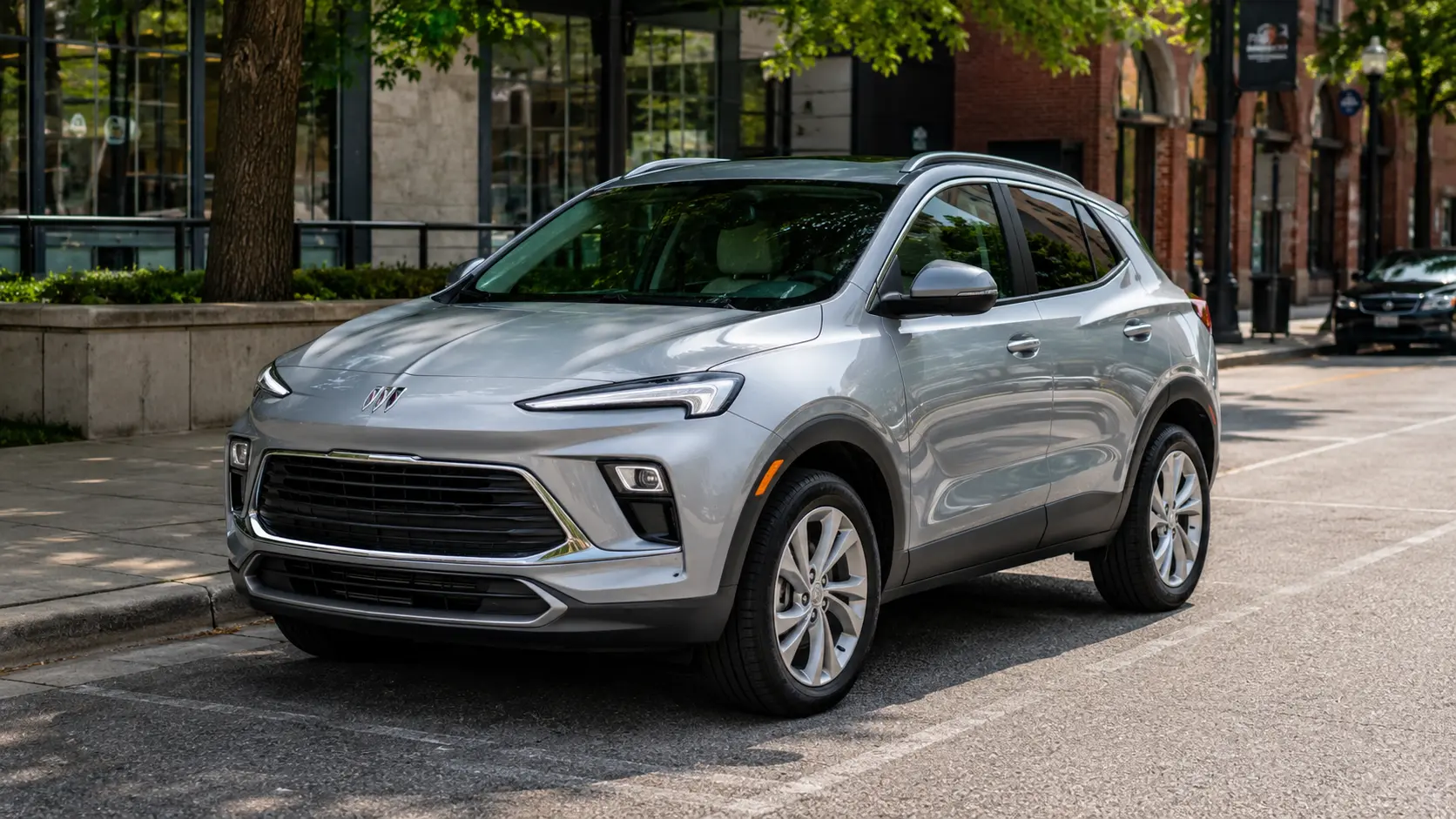 A silver 2026 Buick Encore GX crossover parked on a city street in daylight, shot candidly at a three-quarter angle.