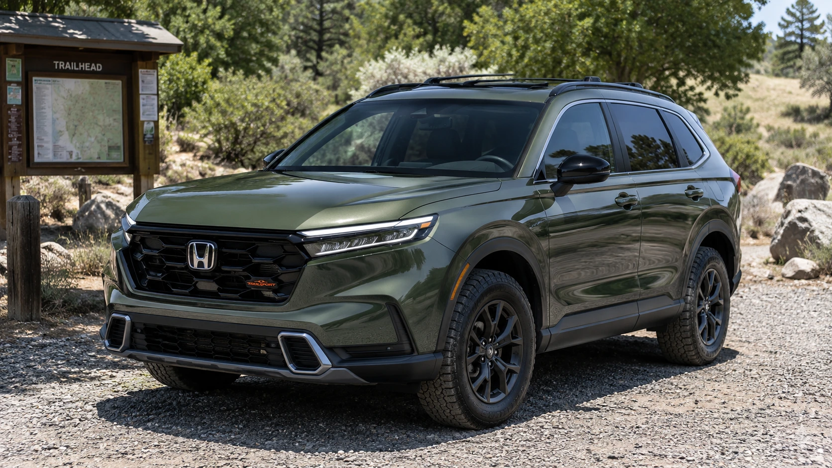 A green 2026 Honda CR-V Hybrid TrailSport parked outside a trailhead in natural daylight, shot candidly at a three-quarter angle.