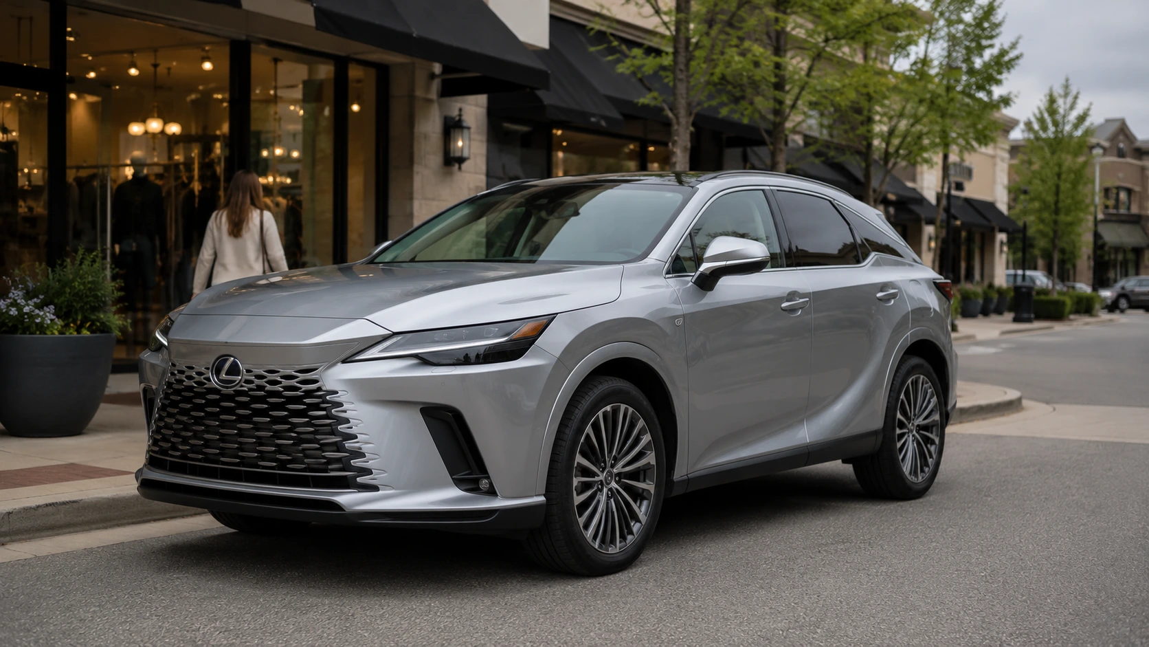 A silver 2026 Lexus RX parked outside an upscale suburban shopping center in soft overcast daylight, shot in a candid three-quarter angle.