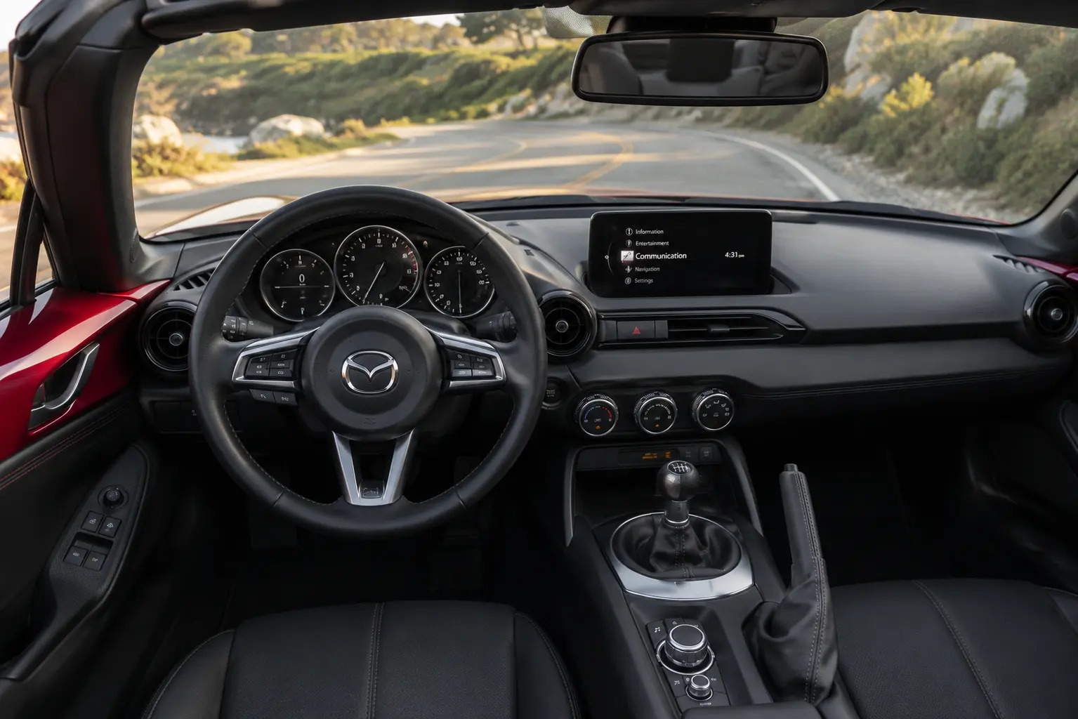 The compact, driver-focused cockpit of a Mazda MX-5 Miata, lit by natural daylight.