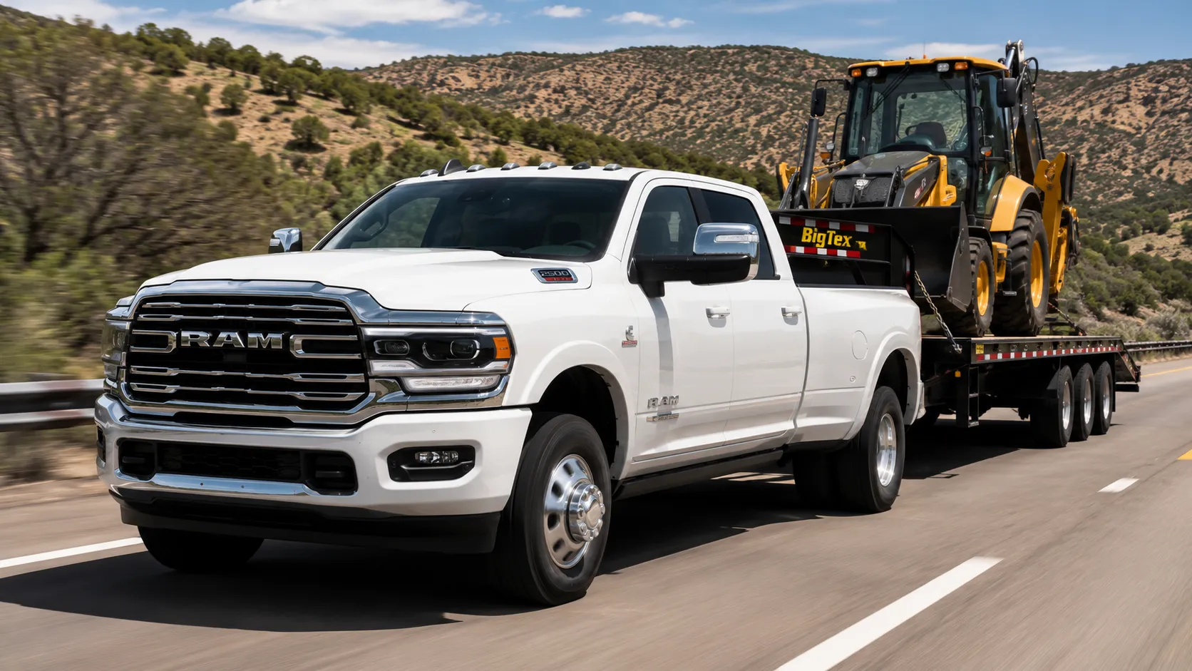 A white 2026 Ram 2500 heavy-duty pickup truck towing a trailer on a highway in daylight, shot candidly at a three-quarter angle.