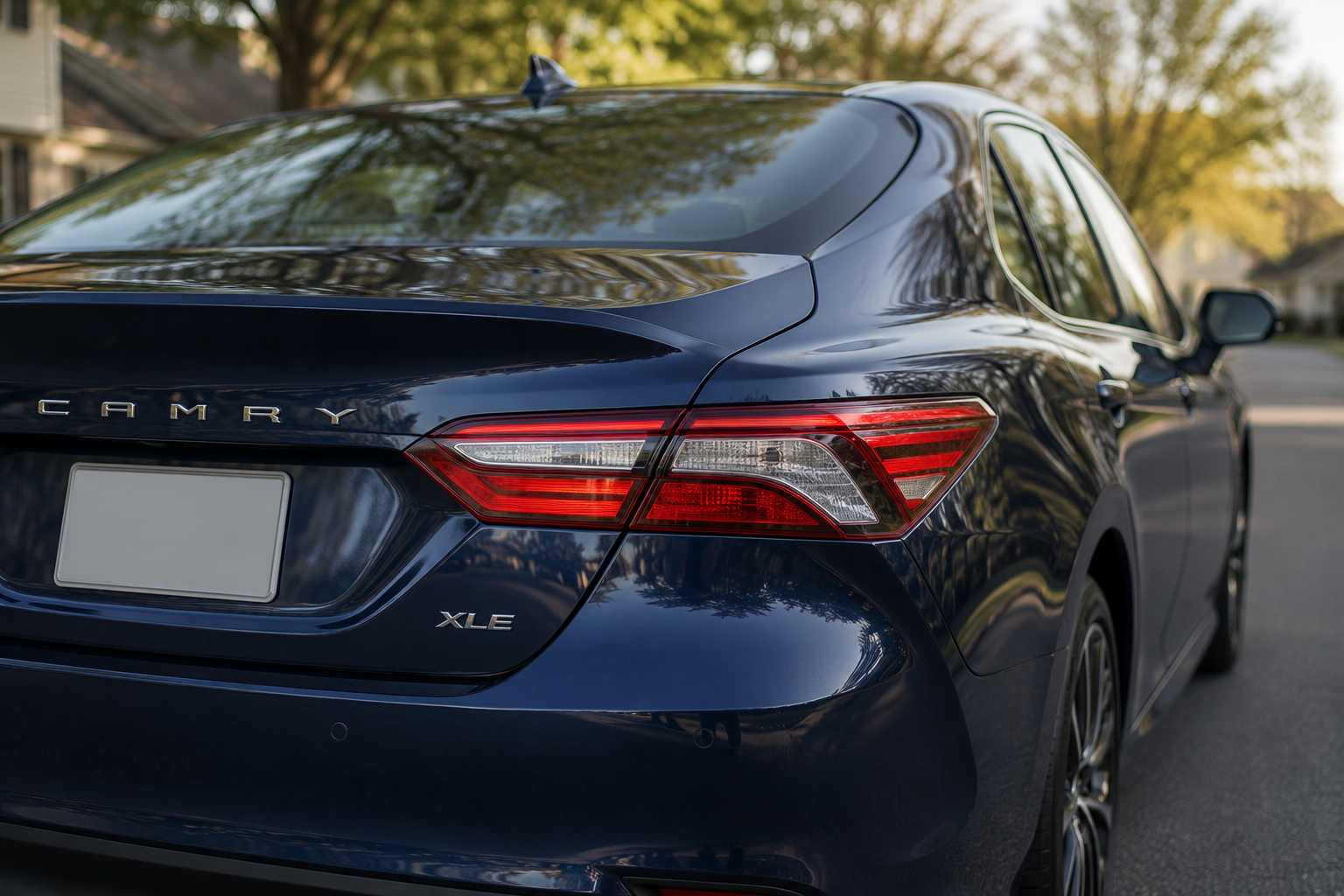 A close-up of the Toyota Camry's rear three-quarter view showing its taillight and trunk lines in soft daylight.